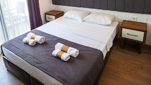 Una habitación de hotel con una cama grande, dos mesitas de noche y una ventana con cortinas.
