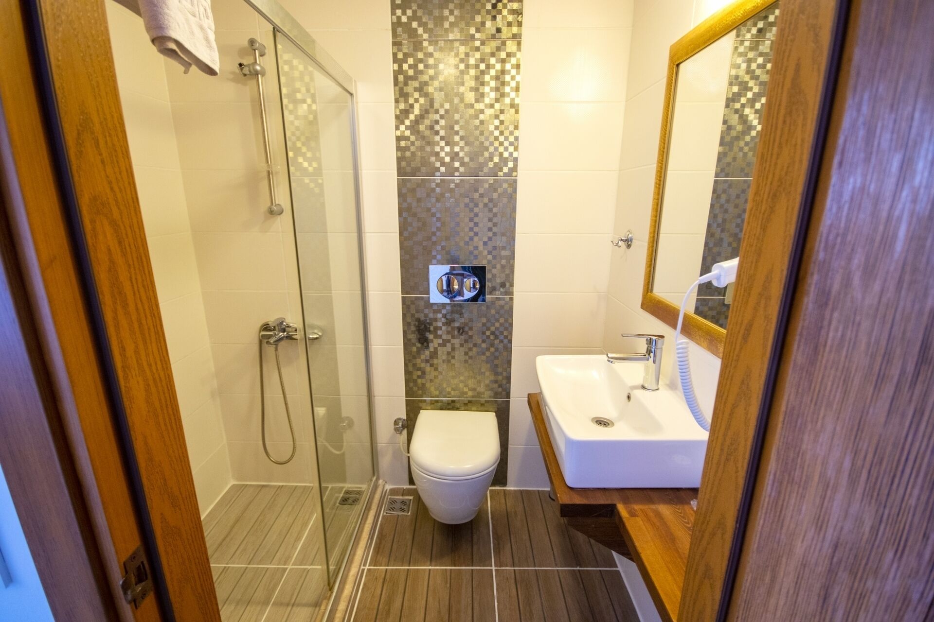 A bathroom with a glass shower enclosure, a toilet, and a sink with a mirror.