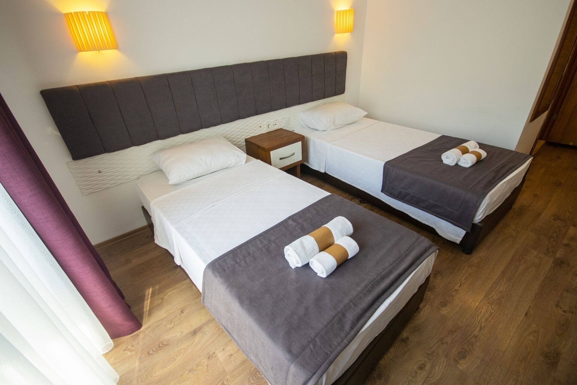 Een hotelkamer met twee bedden, een nachtkastje en wandlampen.