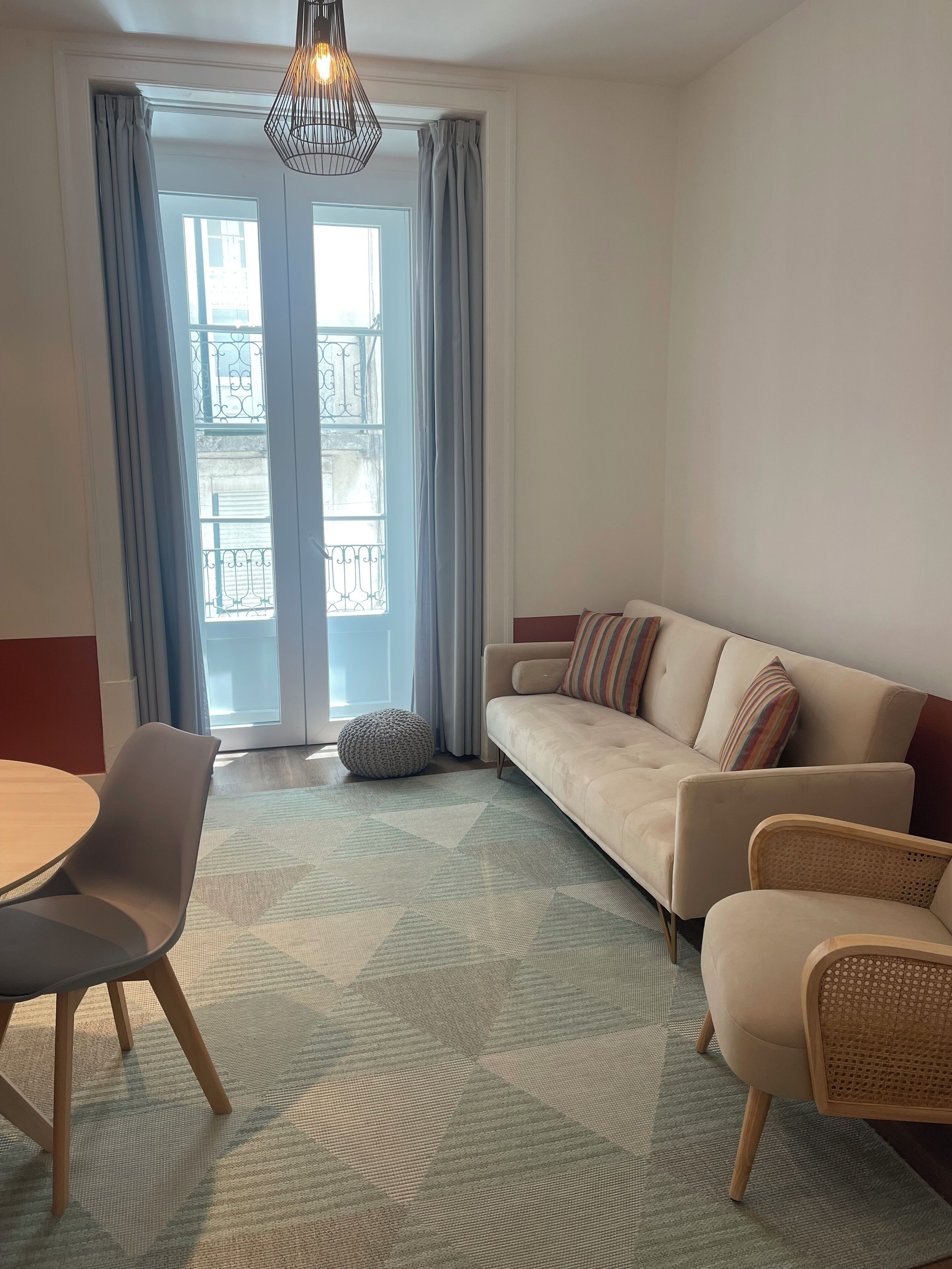 Una sala de estar con un sofá, sillas, una mesa y una alfombra estampada.