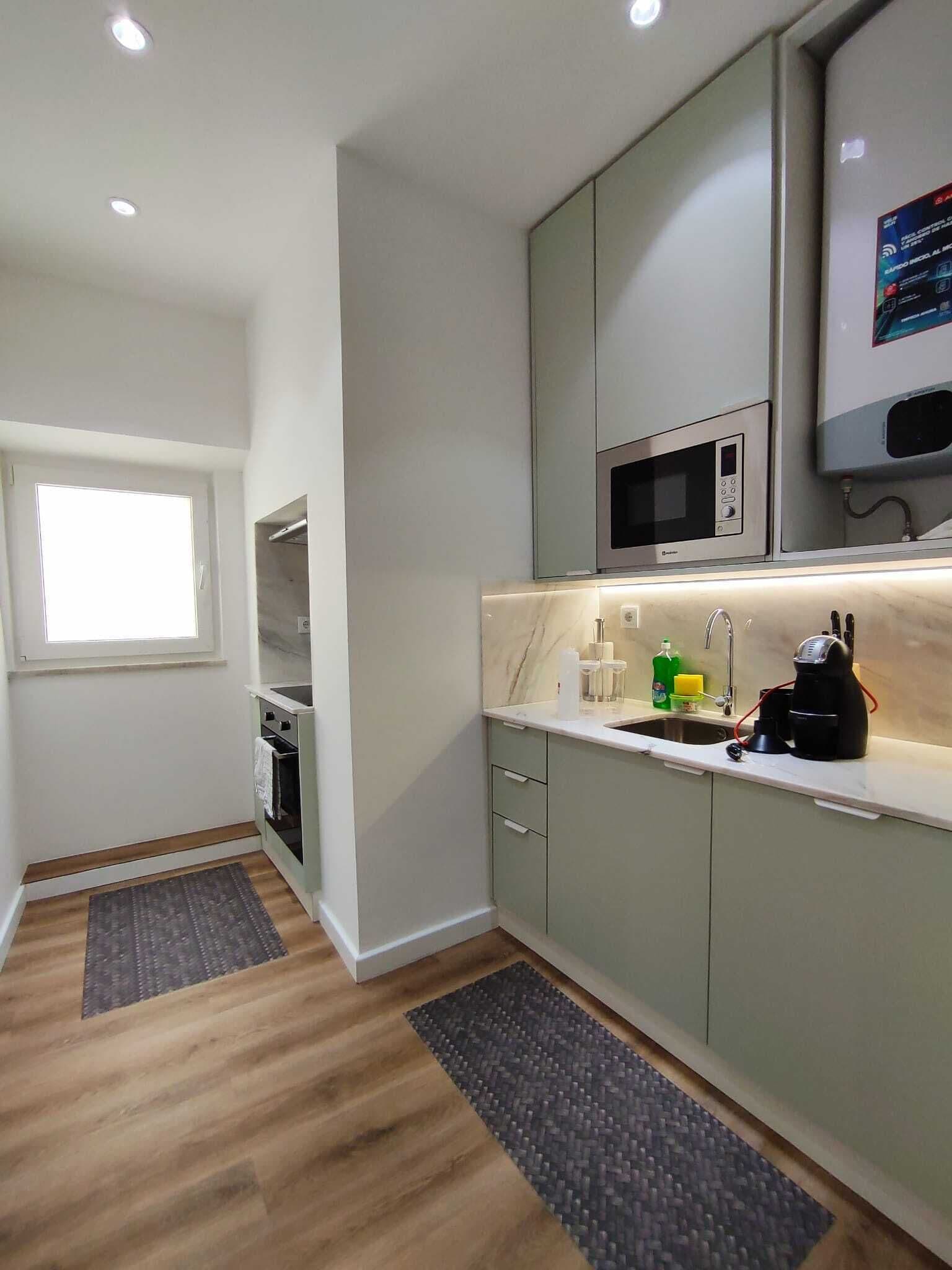 A modern kitchen with a built-in microwave, a sink, and a coffee machine.