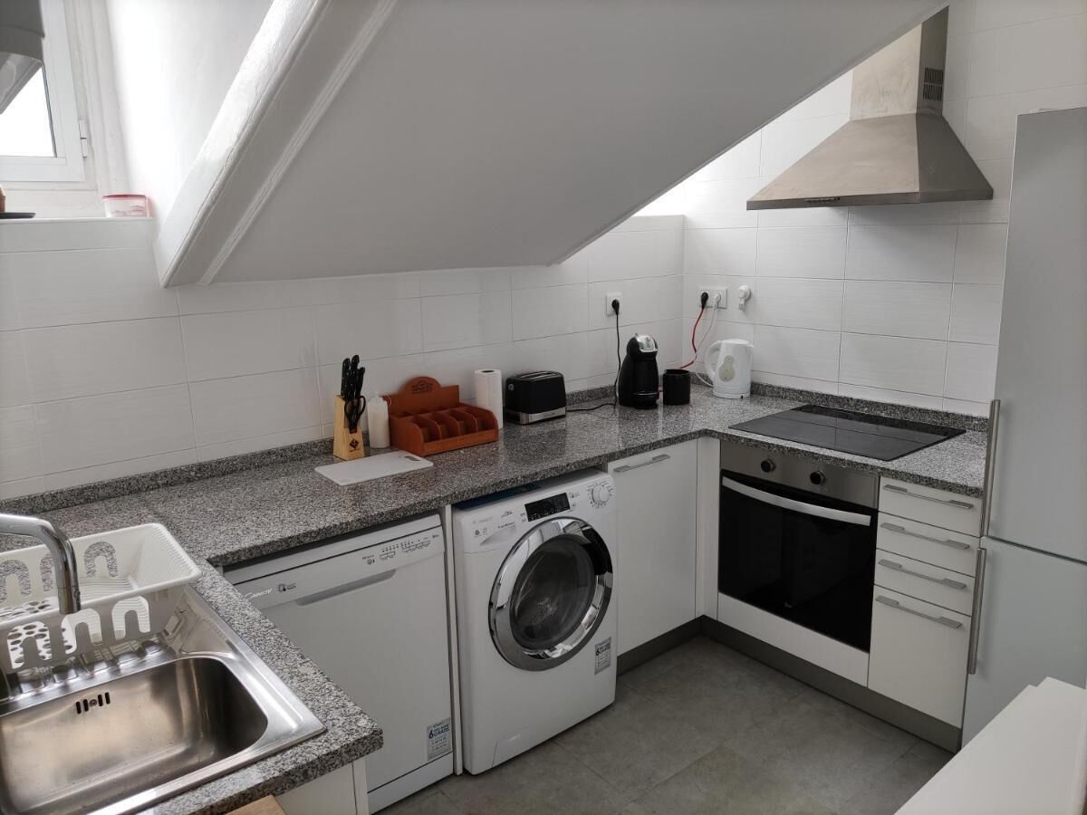 Eine kleine Küche mit Waschmaschine, Backofen und Spüle.