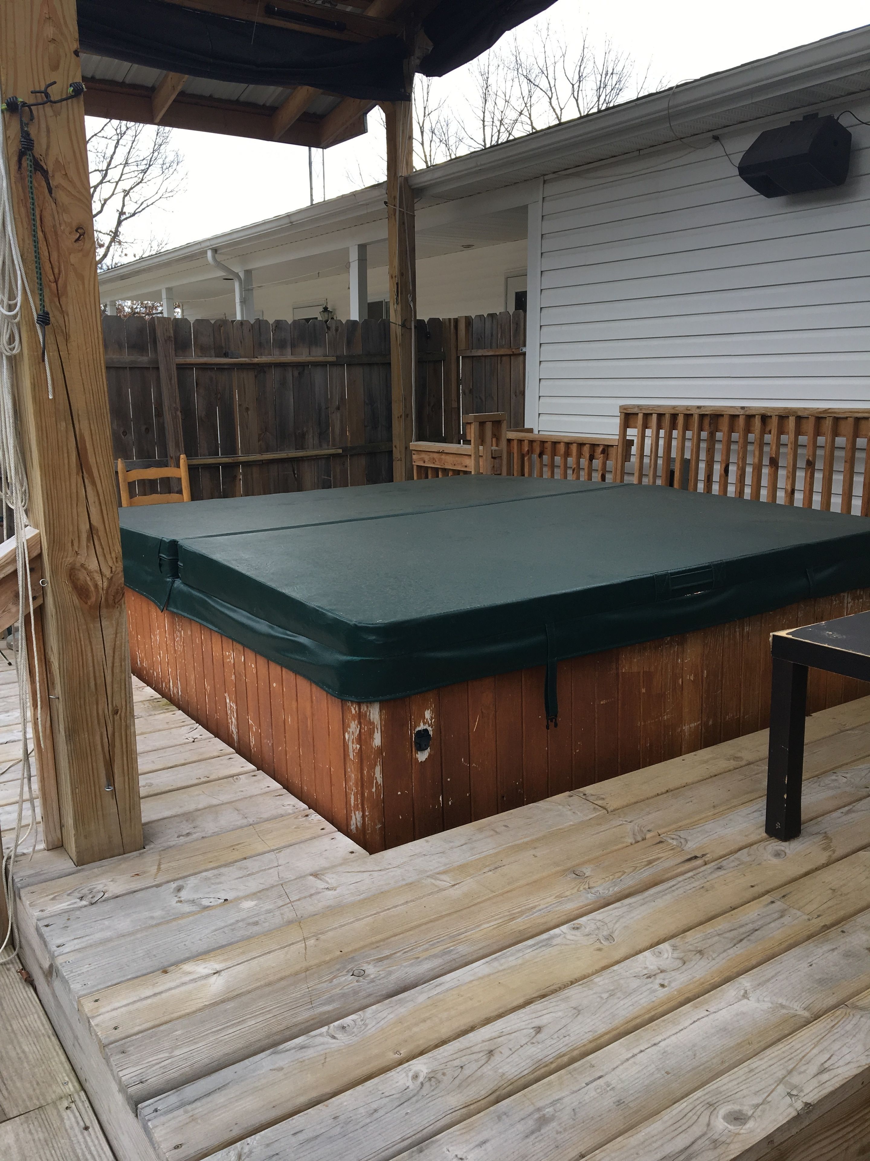 Eine Holzterrasse mit Whirlpool, Holzstühlen und einer überdachten Sitzecke.