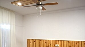 A hotel room with two single beds, a wooden headboard, a small table, and a ceiling fan. - Hostal Miranda (Blanes)