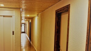 A long, narrow hallway with wooden panel ceilings and a polished floor. - Hostal Miranda (Blanes)