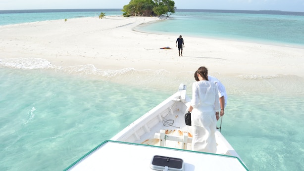 A boat with a clear view of a white sandy beach and turquoise waters.