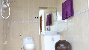 A bathroom with a toilet, a shower, a sink, and a large vase.