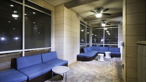 A modern lounge area with blue seating, a small round table, and a ceiling fan. - Springhill Suites Houston Westchase (Houston)