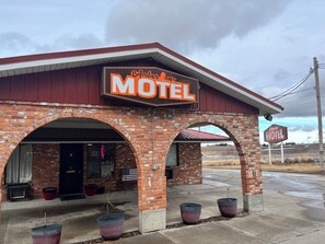 Um motel de tijolos com telhado vermelho e um letreiro neon.