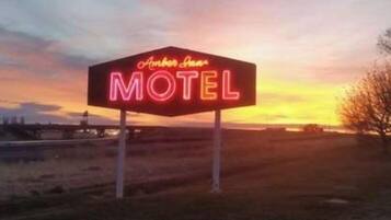 Un letrero de motel neón con el nombre 'Amber Inn' contra un cielo al atardecer.