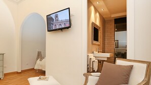 A modern living room with a television, a sofa, and a coffee table. - Madonna de’ Monti Suites  (Rome)