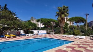 A swimming pool with a checkered floor, surrounded by lounge chairs and palm trees. - Racó d'en Pepe (Calella)