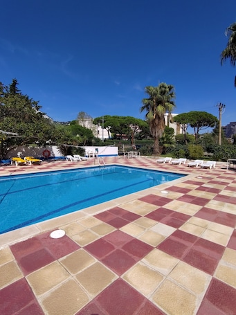 Una piscina al aire libre, sillones reclinables de piscina