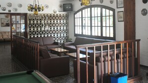 A billiards room with a pool table, leather sofas, and a large arched window. - Racó d'en Pepe (Calella)