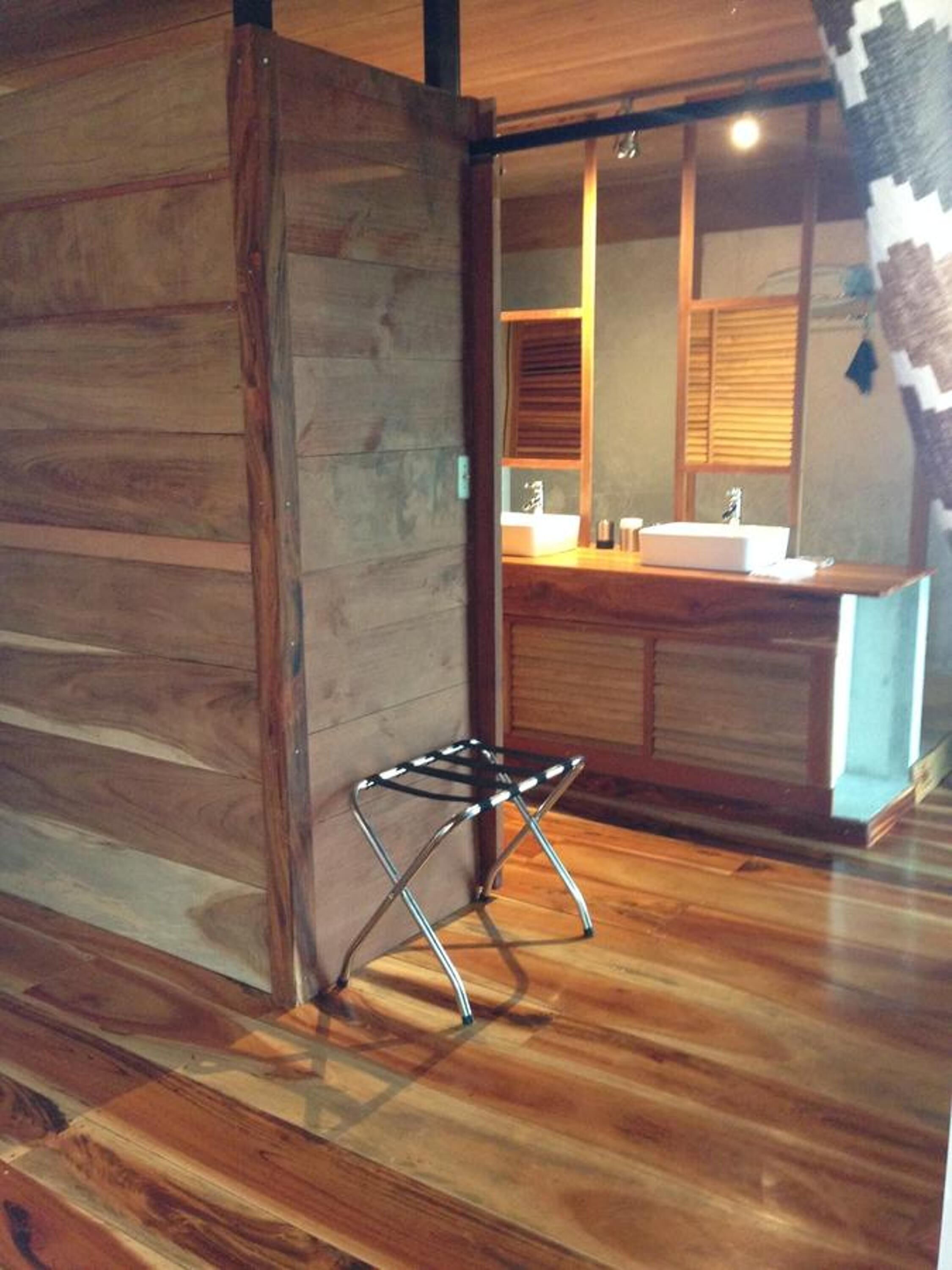 Una cocina moderna con armarios de madera, un lavamanos de acero inoxidable y un taburete de metal negro.