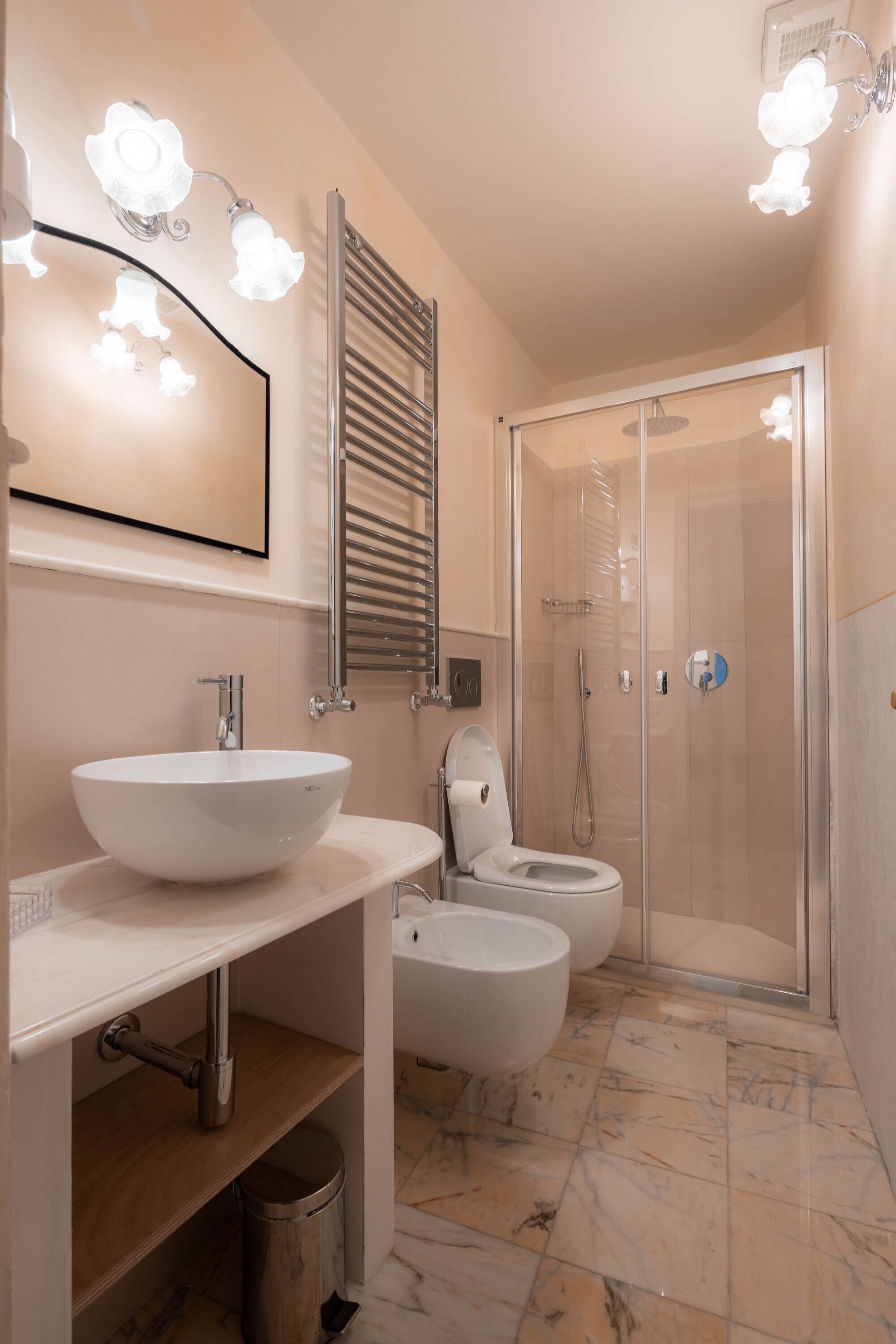 A modern bathroom with a large white sink, a toilet, and a glass-enclosed shower.