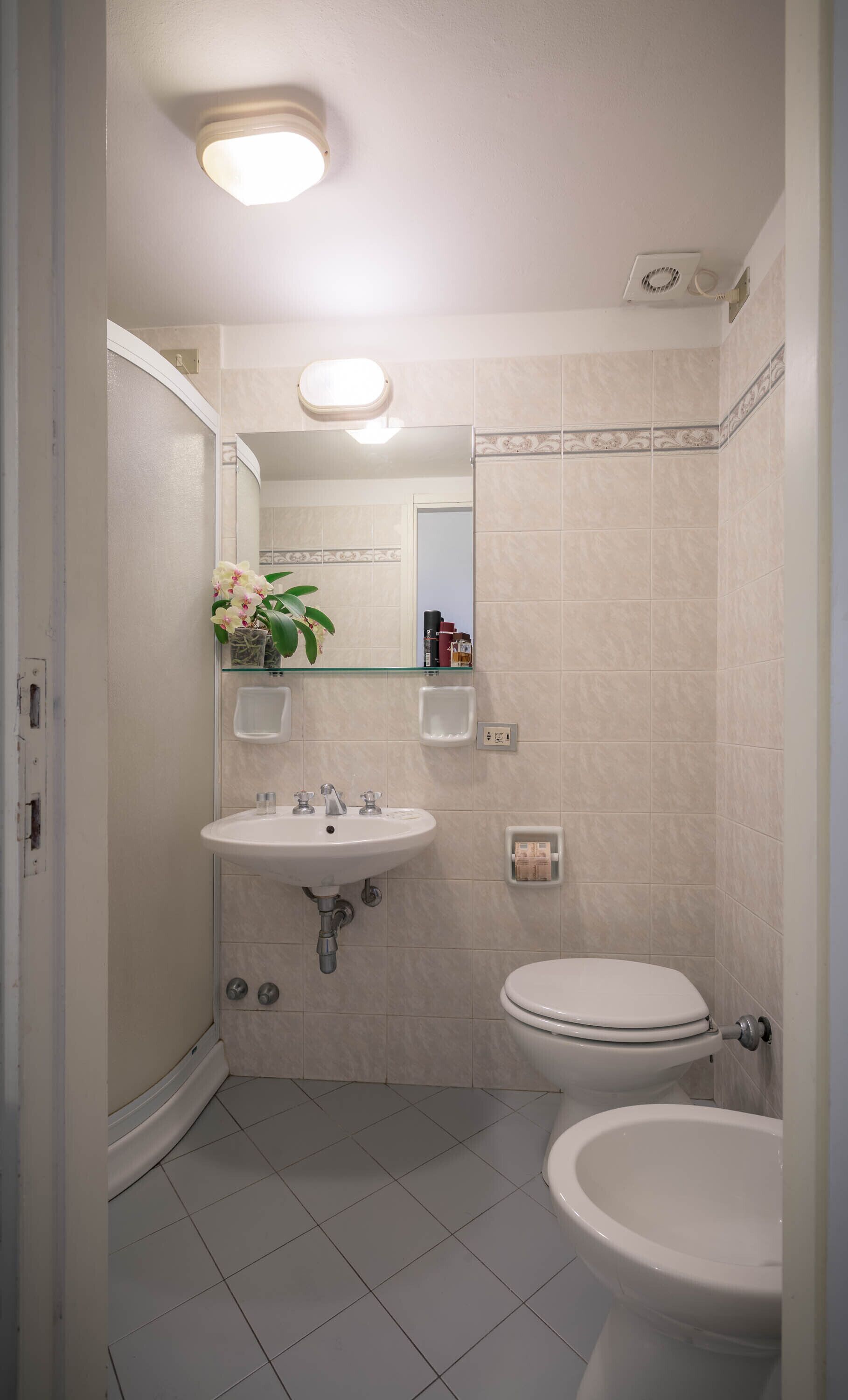 A compact bathroom with a white sink, a toilet, and a shower area.
