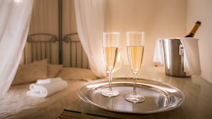 A bed with a canopy, two champagne flutes on a tray, and a champagne bottle in the background. - Novella House (Florence)