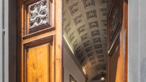 A corridor with ornate wooden doors and a checkered floor, leading to a staircase. - Novella House (Florence)