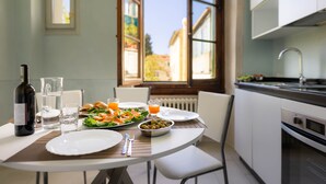 A dining table set with plates, glasses, a bottle, and a bowl of olives. - Novella House (Florence)