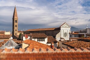 A historic town with a prominent church tower and a white building with a circular window. - Novella House (Florence)