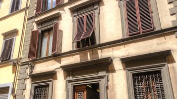 A multi-story building with a classic architectural style, featuring a wooden door and shutters on the windows.
