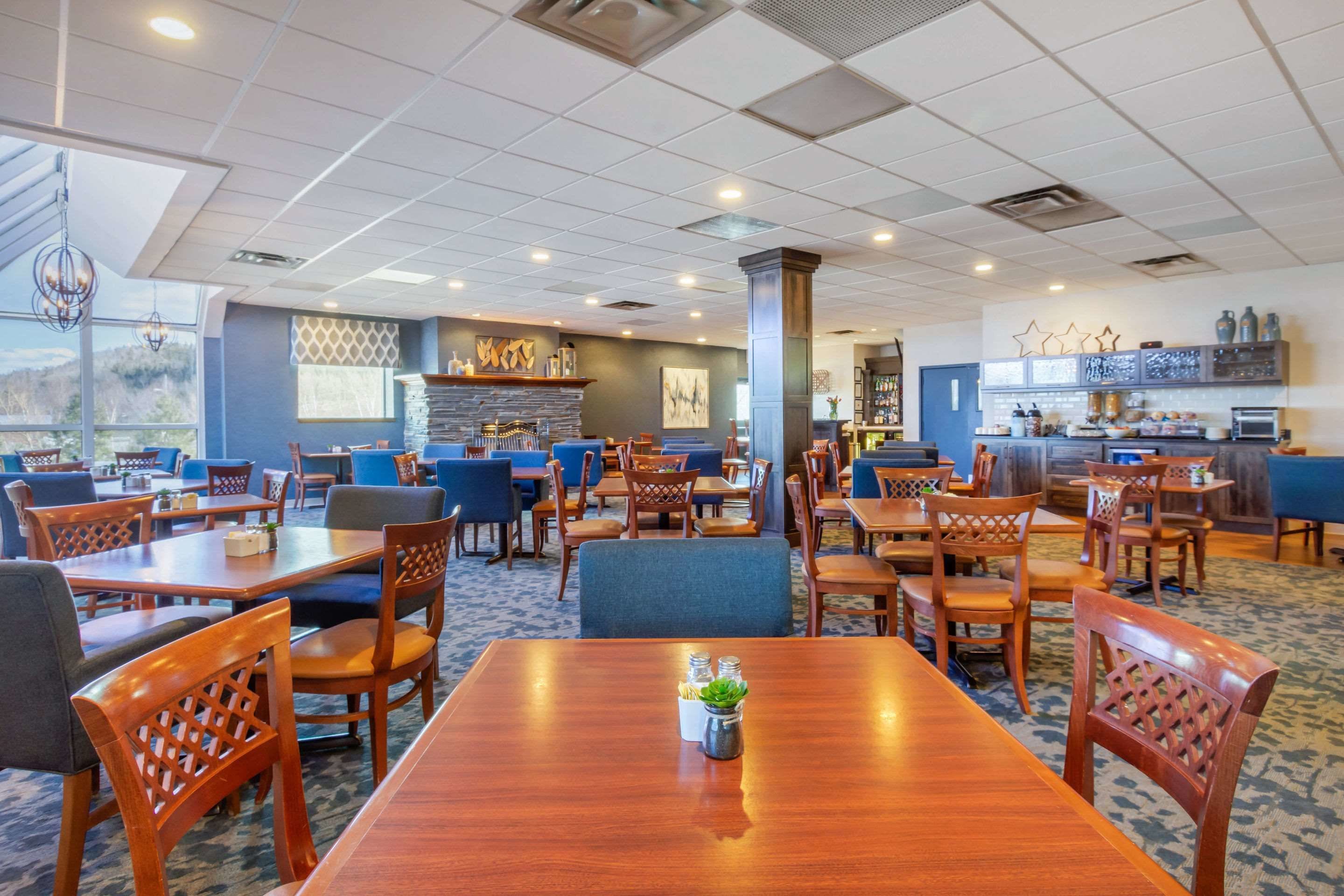 A spacious restaurant with multiple tables and chairs, a bar area, and a view of the outdoors.