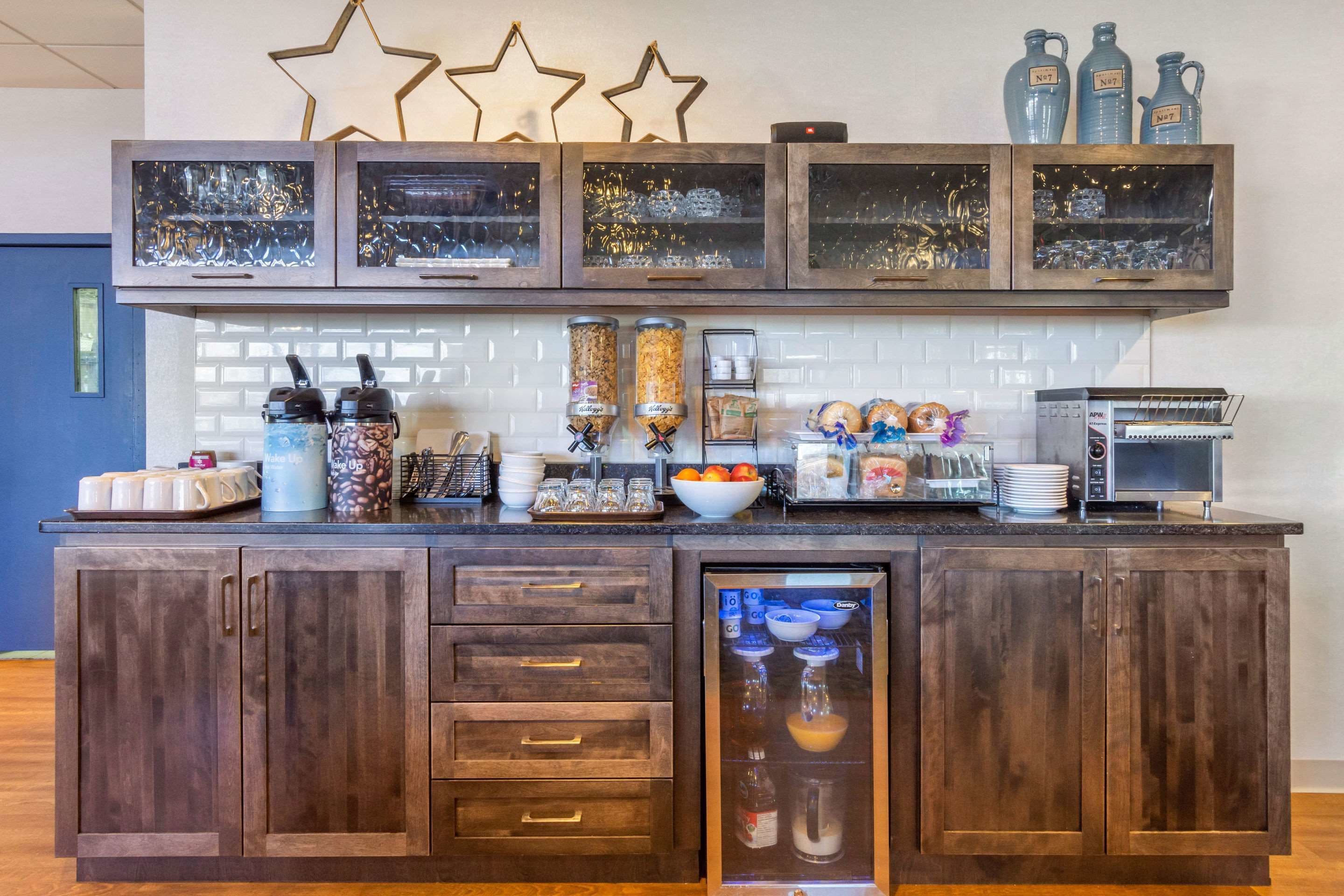 A kitchen with a built-in coffee station, a microwave, and a refrigerator.