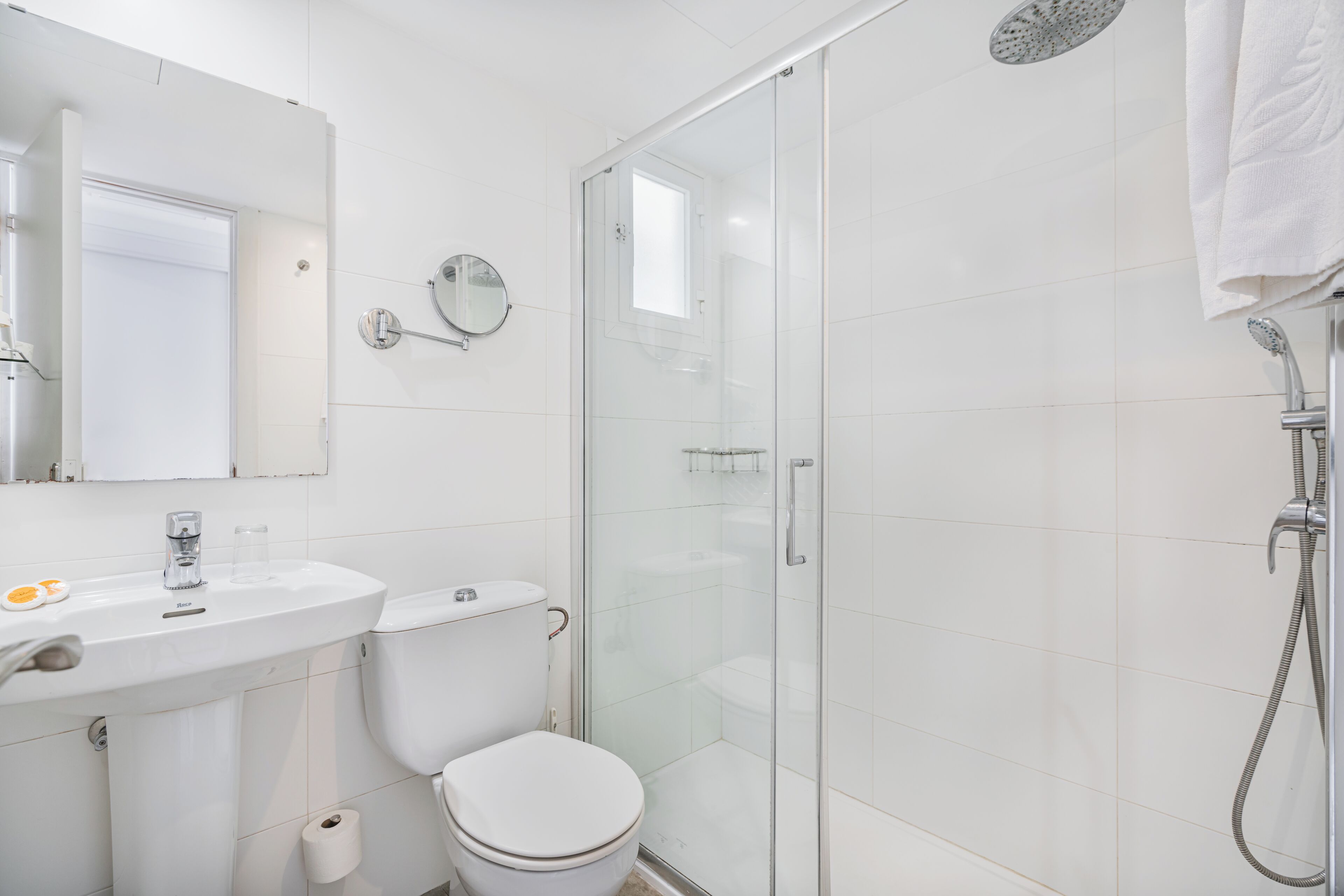 A modern bathroom with a glass-enclosed shower, a toilet, and a sink with a mirror above it.