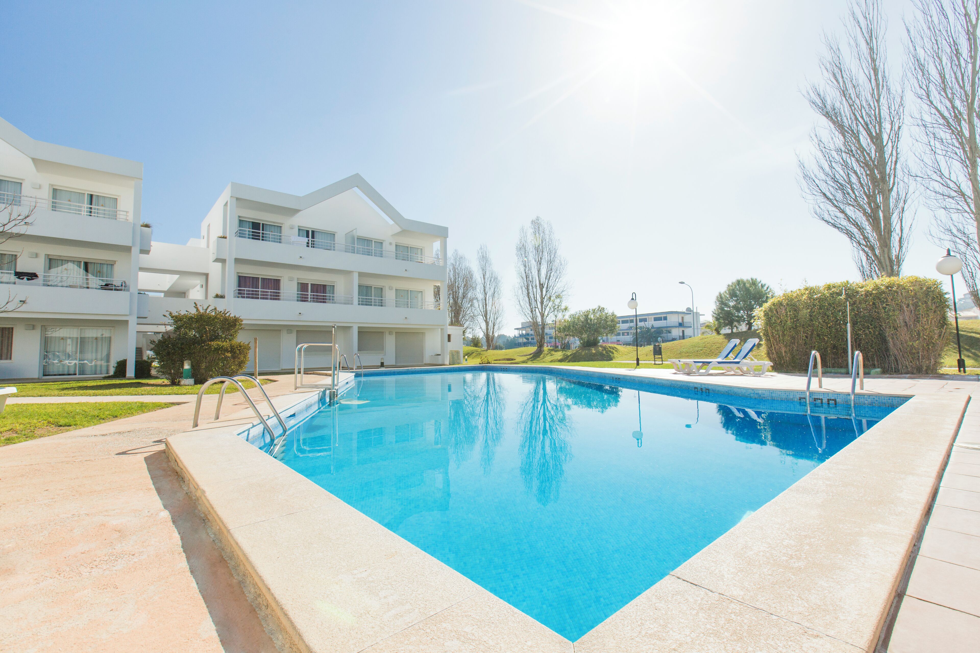 Une piscine rectangulaire à l’eau d’un bleu limpide, entourée d’une terrasse carrelée aux couleurs claires.