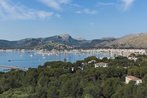 A coastal town with a marina, surrounded by mountains and dense forests. - Apartamentos Habitat (Pollenca)