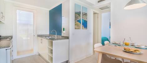 A modern kitchen with white cabinets, a granite countertop, and a dining area with a table and chairs.