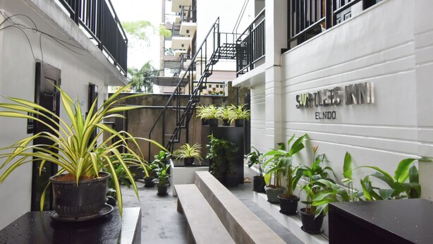A narrow alleyway with potted plants, a bench, and a staircase leading to an upper floor. - Swiftlets Inn (El Nido)