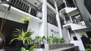 A multi-level atrium with potted plants, a staircase, and a sign reading "SMILEHOUSE." - Swiftlets Inn (El Nido)