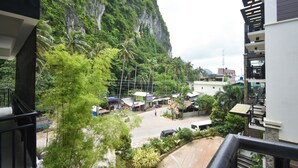 A view from a balcony overlooking a street with buildings, palm trees, and a mountain in the background. - Swiftlets Inn (El Nido)
