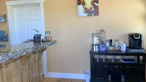 A kitchen with a granite countertop, a coffee maker, and a cabinet with jars. - Teton Valley Motel (Victor)