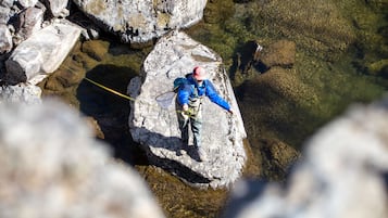 Una persona haciendo rappel por un acantilado rocoso hacia un cuerpo de agua cristalina.