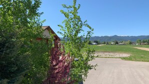 A rural road with a house on the left and a clear view of mountains in the distance. - Teton Valley Motel (Victor)