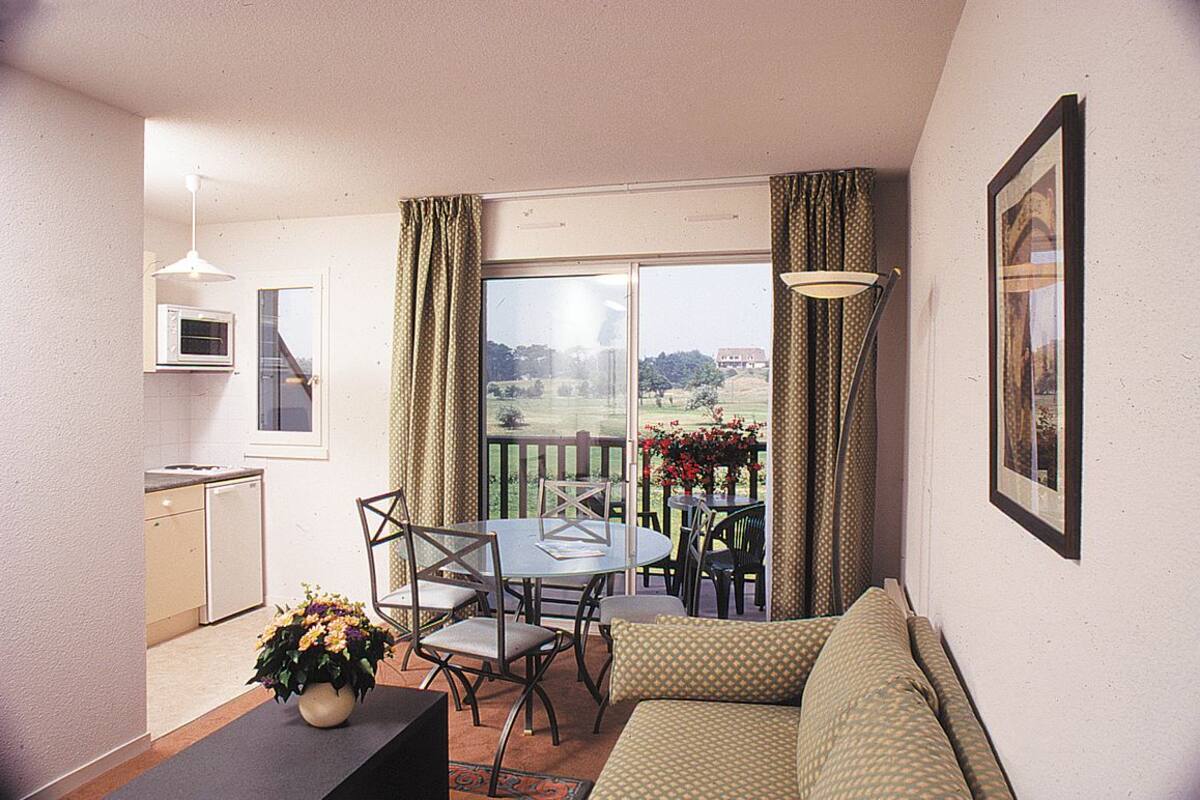 Ein kompakter Wohnbereich mit Balkon, Esstisch und einer Sitzecke.