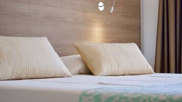 A neatly made bed with two pillows, a headboard with a light fixture, and a patterned bedspread.