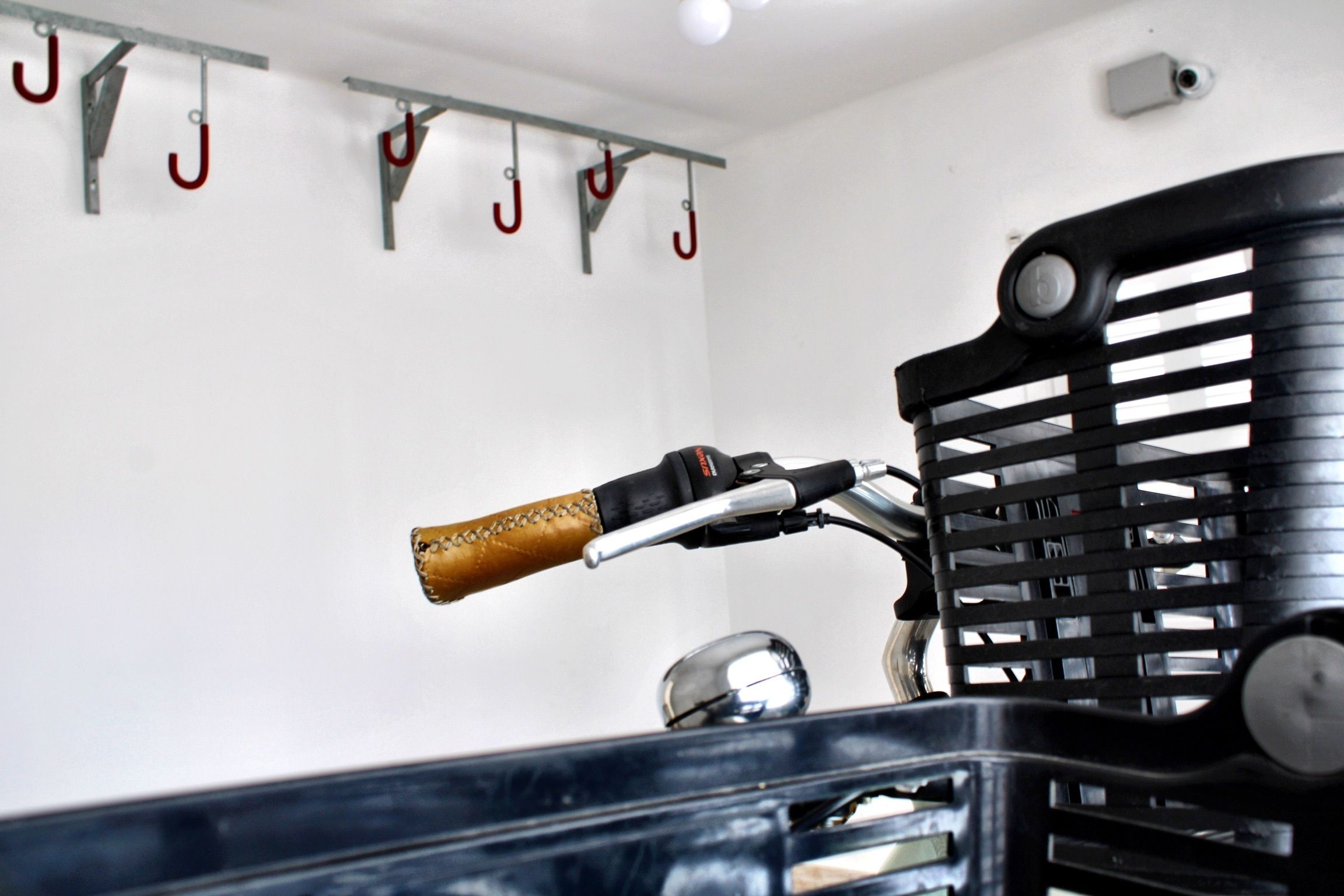 Un vélo avec un guidon en cuir et un panier noir fixé à l’avant.