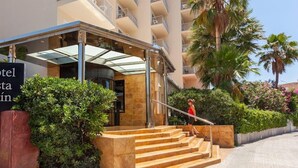Een hotel ingang met overdekte veranda, trappen en een bord.