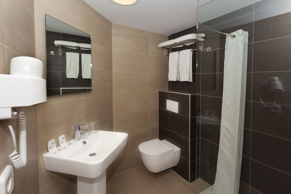 Un baño moderno con lavamanos, inodoro y ducha.