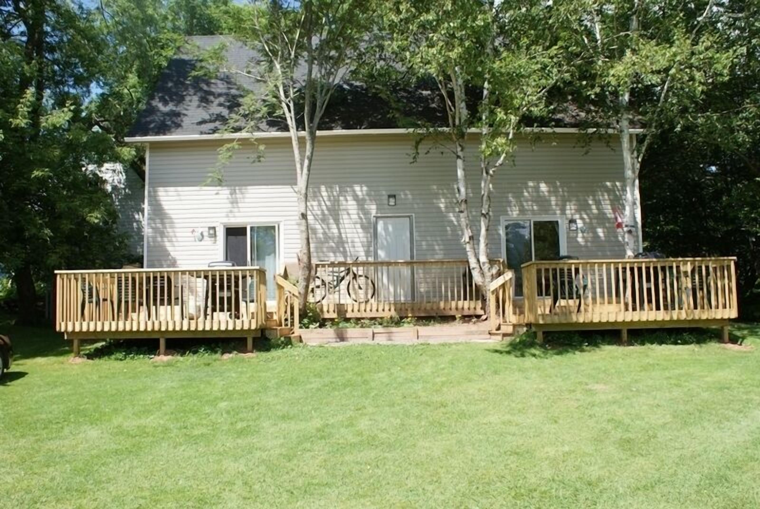 A single-story house with a front porch, a small front yard, and a wooden deck.