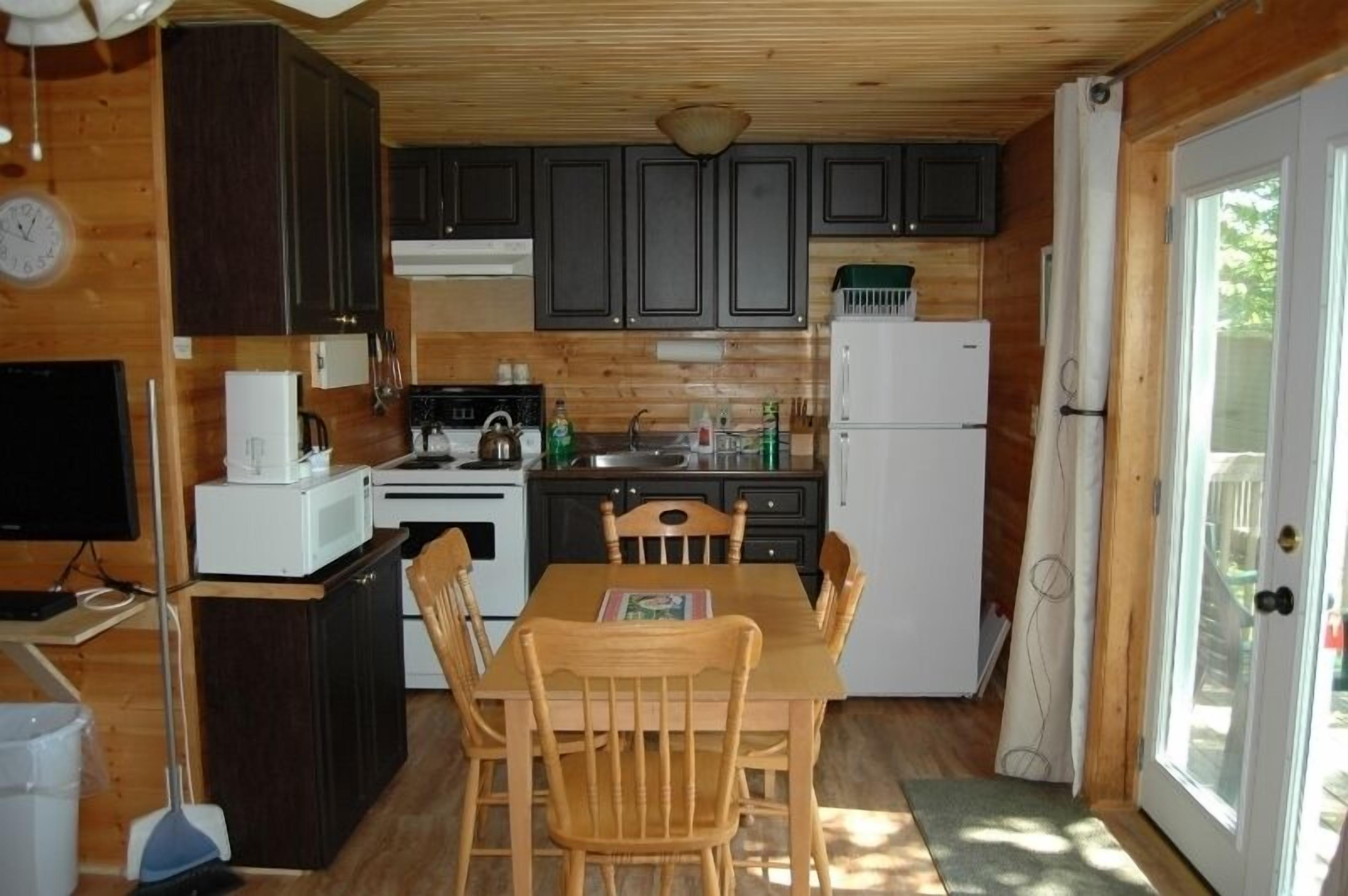 Cocina compacta con armarios de madera, microondas, estufa y refrigerador.