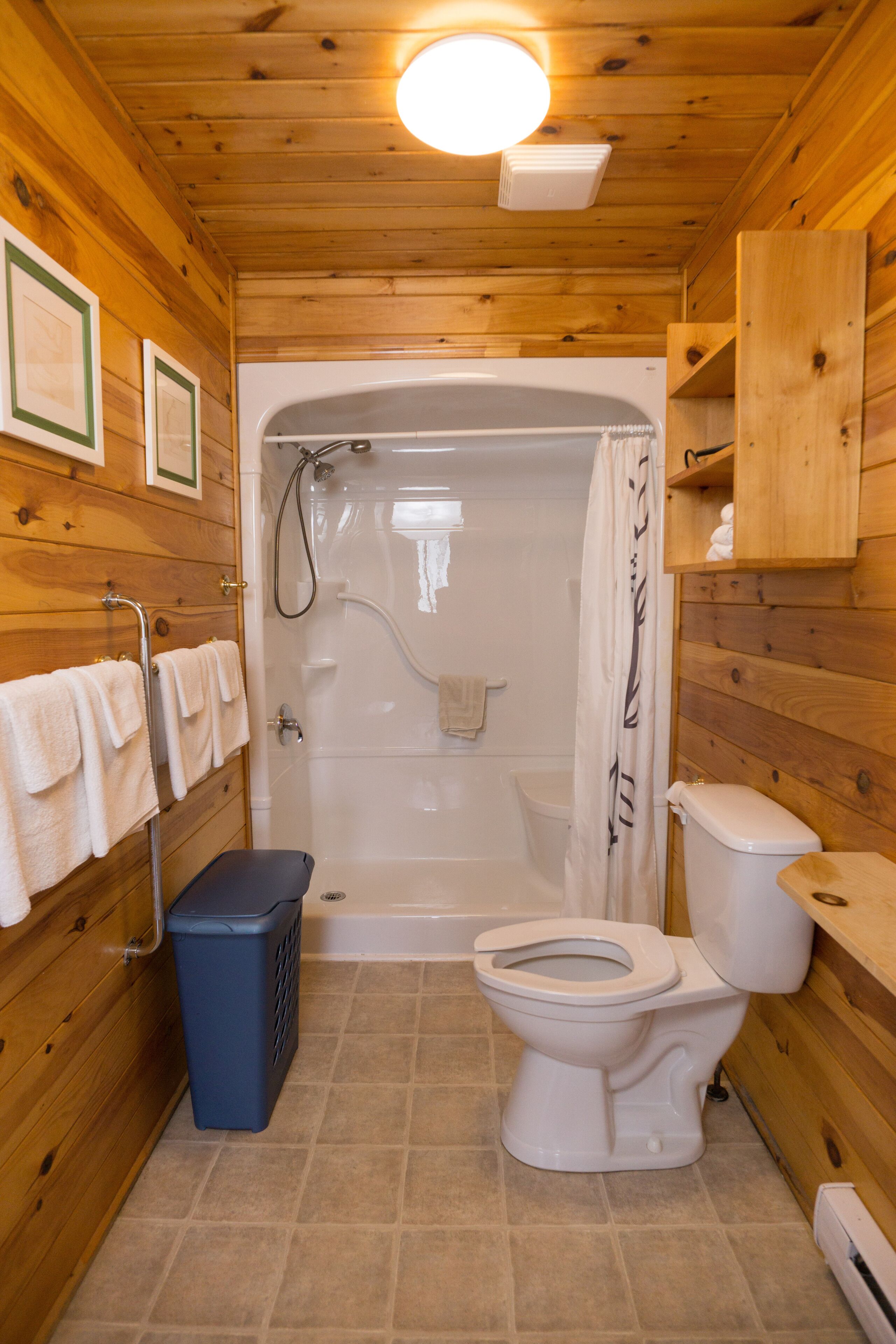 A wooden cabin bathroom with a shower, toilet, and laundry basket.