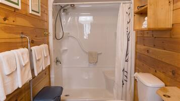 A wooden cabin bathroom with a shower, toilet, and laundry basket.