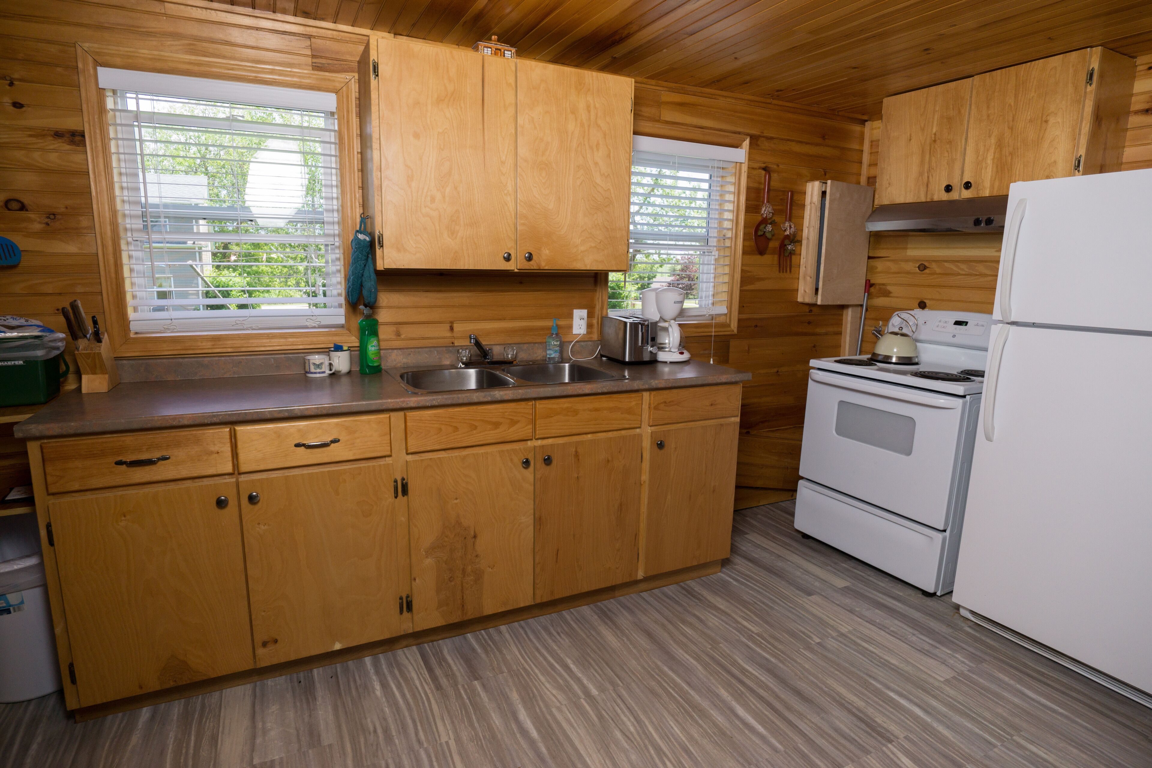 A kitchen with wooden cabinets, a stove, a sink, and a refrigerator.