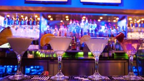 Un bar avec trois verres à martini posés sur le comptoir, chacun orné d’un garnissement différent.