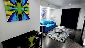 Una sala de estar moderna con un sofá azul, una mesita de centro y arte abstracto en las paredes.